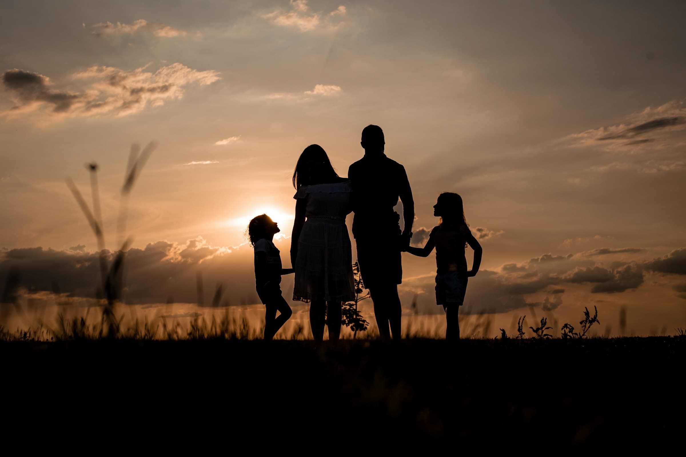 NJ family silhouetted against a sunset